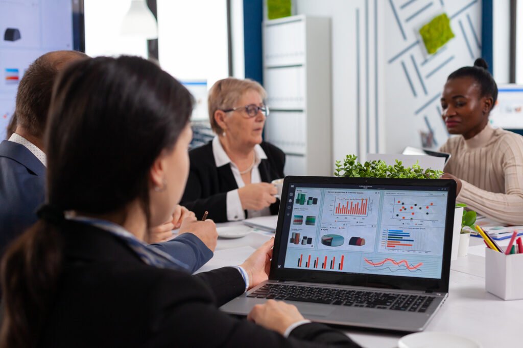 Young woman analysing charts on laptop in business meeting room